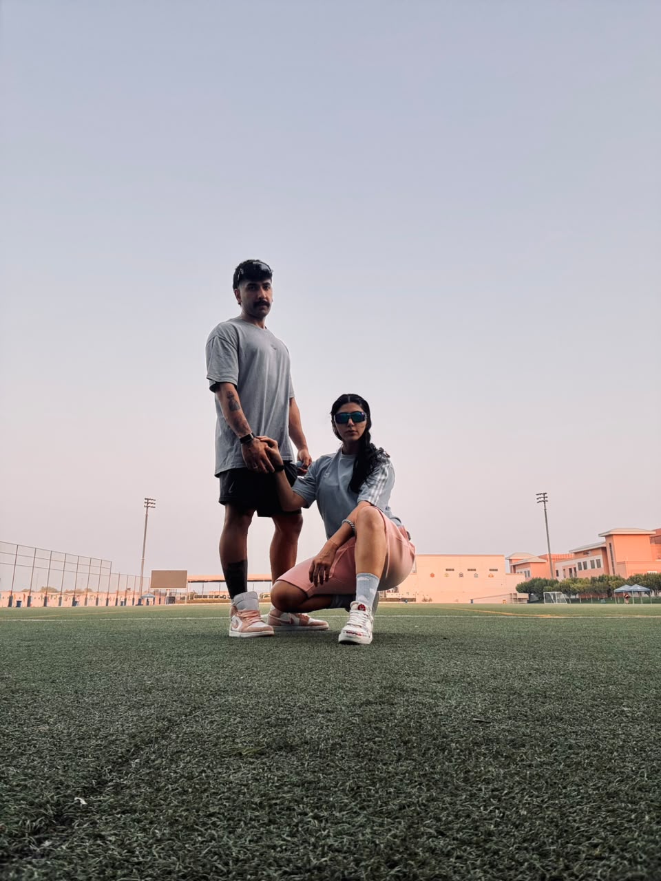 Sadaf and Arash posing on a sports field at sunset
